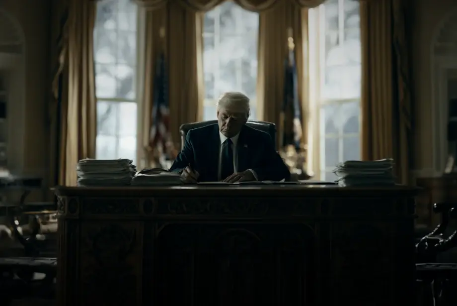 Donald Trump sitting on his desk while filling out some documents.