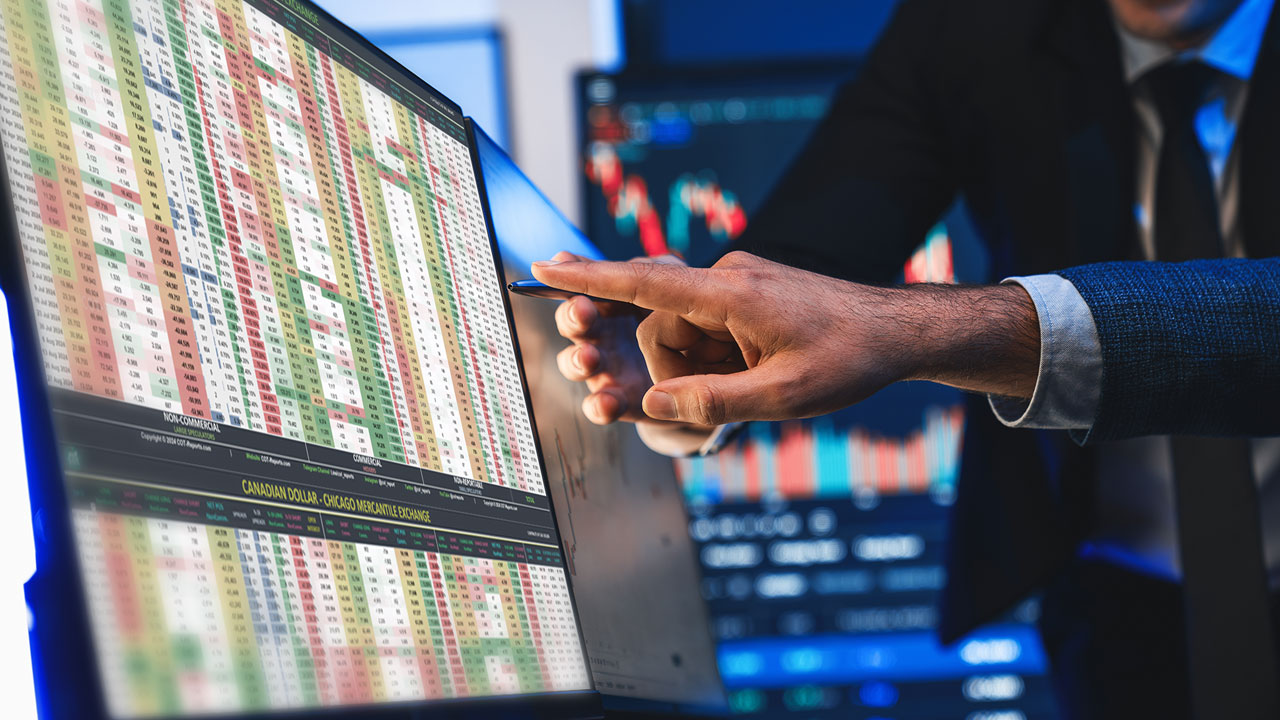 Commitment of Traders: What are COT Reports & How to Read Them – A financial analyst pointing at a trading screen displaying COT data, market positions, and price trends with financial charts in the background.
