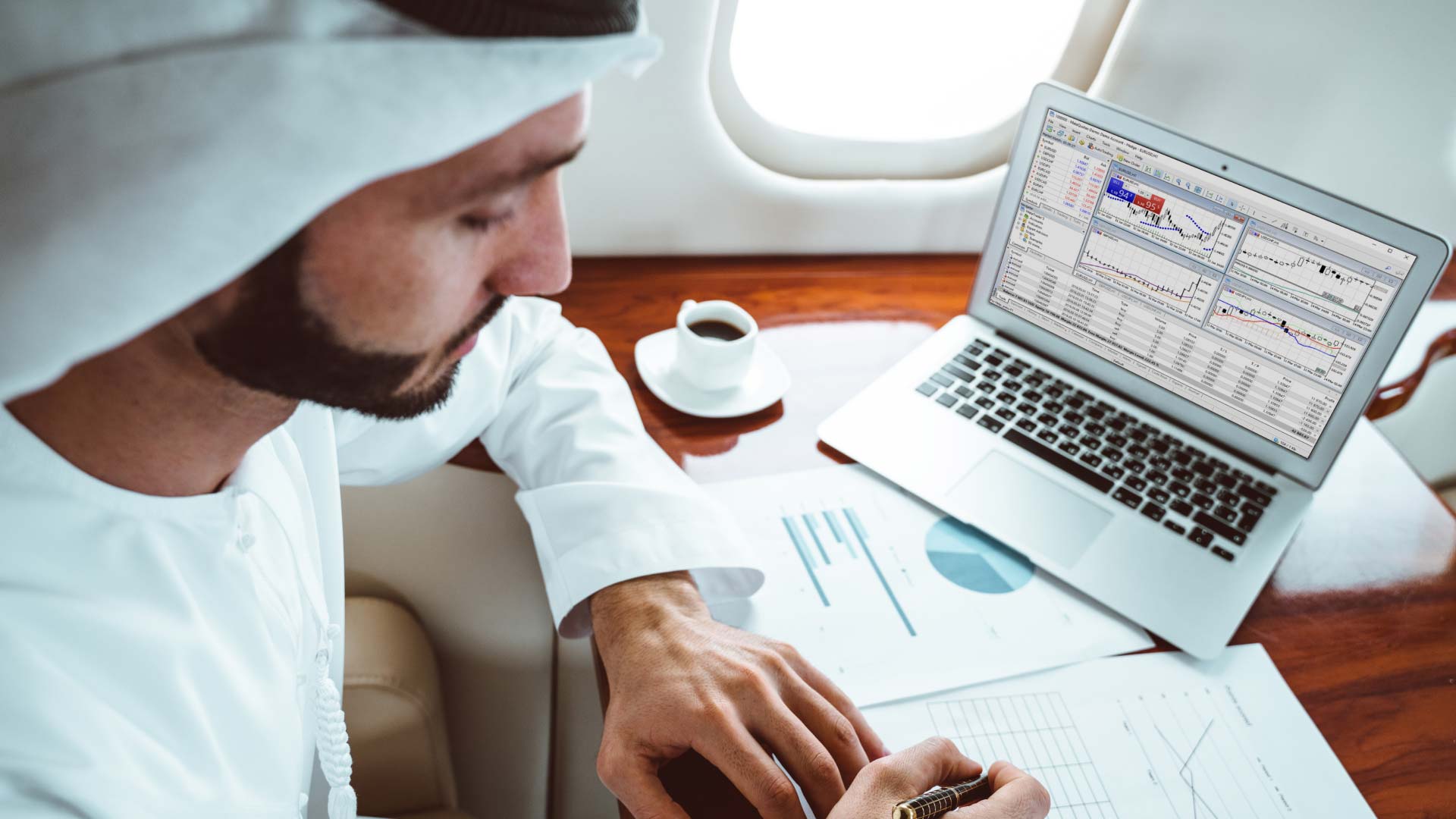 Is Forex Trading Halal or Haram? – A man in traditional Middle Eastern attire analyzing financial charts with a trading platform open on a laptop, representing the discussion of forex trading in Islamic finance.